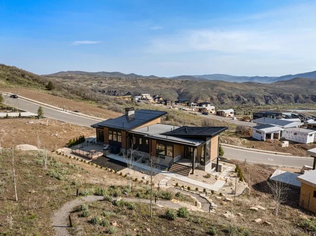 Modern architectural design with a flat roofline, wood-clad exterior accents, and a stone chimney feature