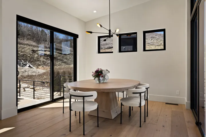 Wide-plank wood-finish flooring, white walls, black-framed sliding glass door, and recessed lighting