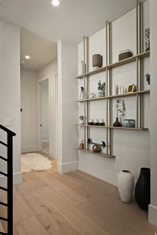 Hardwood flooring, recessed ceiling lighting, and built-in shelving with vertical accents
