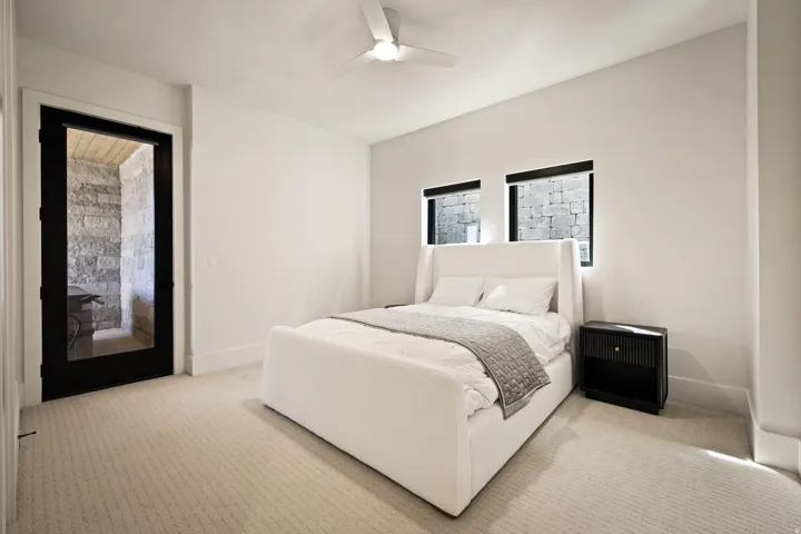 Recessed windows with black trim, ceiling fan, neutral-toned carpeting, and a black-framed glass door