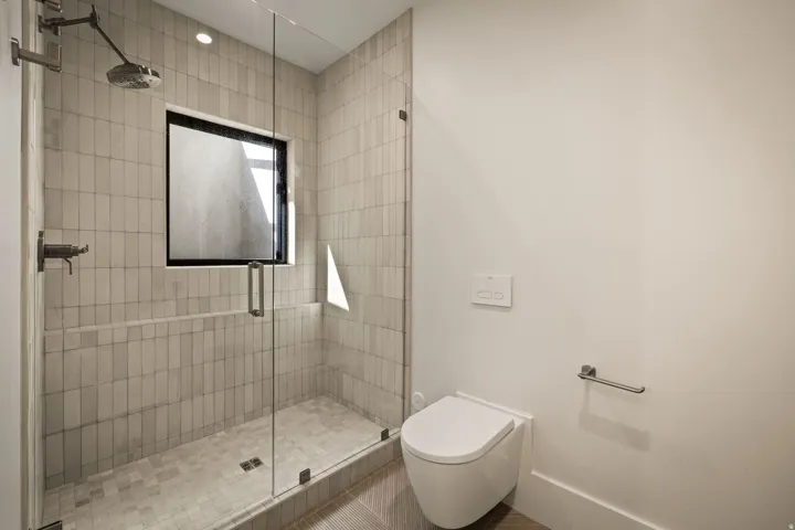 Glass-enclosed shower with vertical tile surround and integrated window