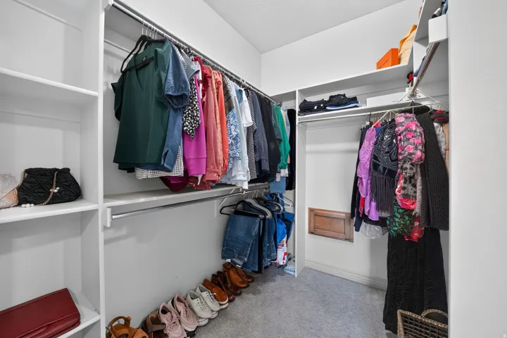 Built-in closet organization system featuring multiple shelves, dual hanging rods, and neutral-toned carpeting