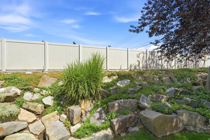 Rock landscaping with lush ground cover and a privacy fence