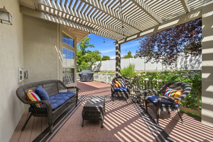 Covered patio with an open lattice pergola, textured exterior wall, and multi-level windows