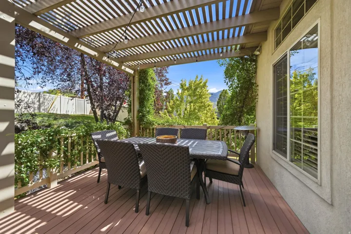 Expansive outdoor deck featuring a slatted pergola, wood-finish decking, and mountain scenery