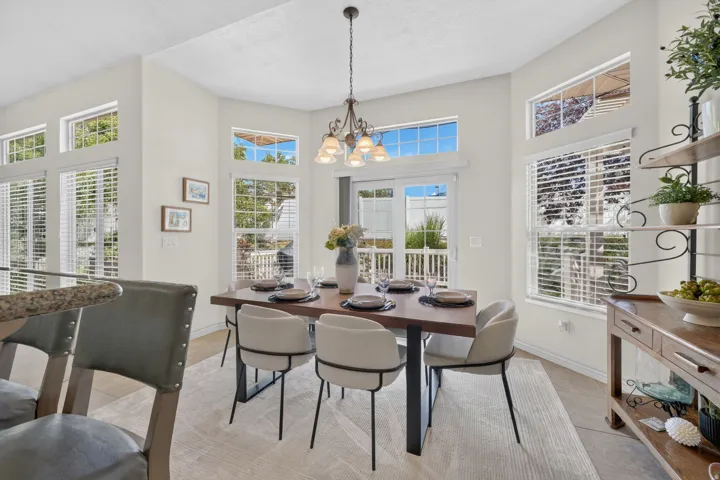 Dining area featuring multiple windows, a sliding glass door, an overhead chandelier, and tile flooring