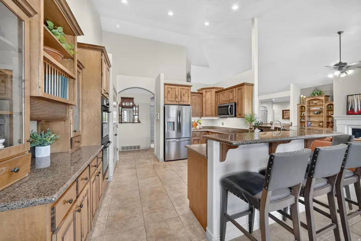 Kitchen featuring wood cabinetry, stainless steel appliances, granite countertops, and tiled flooring