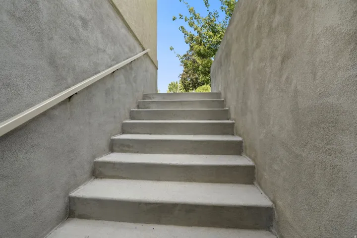 Concrete staircase with stucco walls and a light-colored handrail