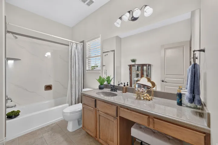 Built-in vanity with wood-finish cabinetry, a single basin sink, and a full-width mirror
