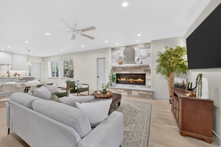 Open-concept living area with a stone fireplace, recessed lighting, and wood-finish flooring