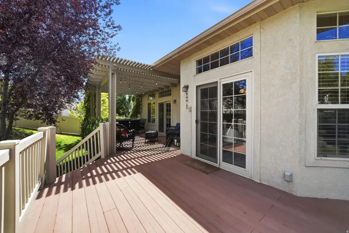 Expansive wood-finish deck with a pergola, a partial privacy fence, and large window installations