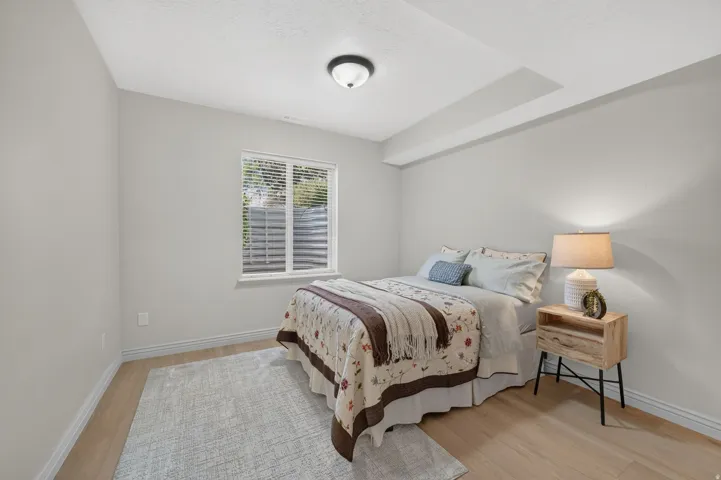 Light-toned wood-finish flooring, white trim, and a window with blinds