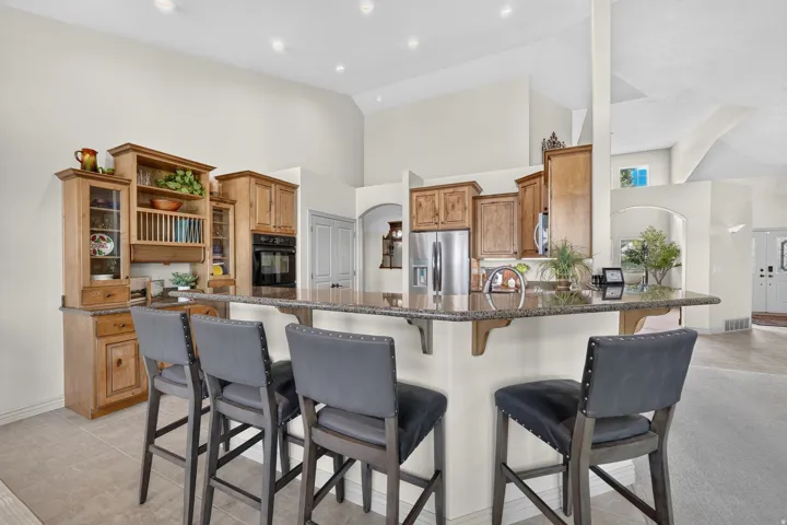 Spacious kitchen featuring a peninsula with countertop seating, stainless steel appliances, wood cabinetry, and vaulted ceilings