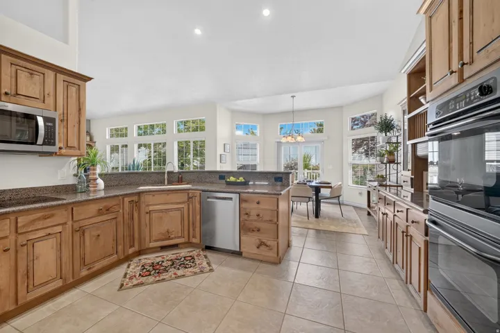 Kitchen featuring wood cabinetry, integrated stainless steel appliances, and tile flooring