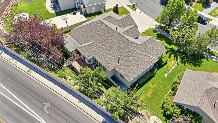Expansive property featuring an asphalt shingle roof, wood-tone deck, and mature trees