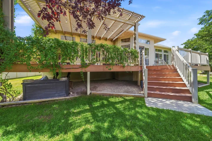 Spacious exterior deck with a decorative pergola, integrated staircase, and ample outdoor living space