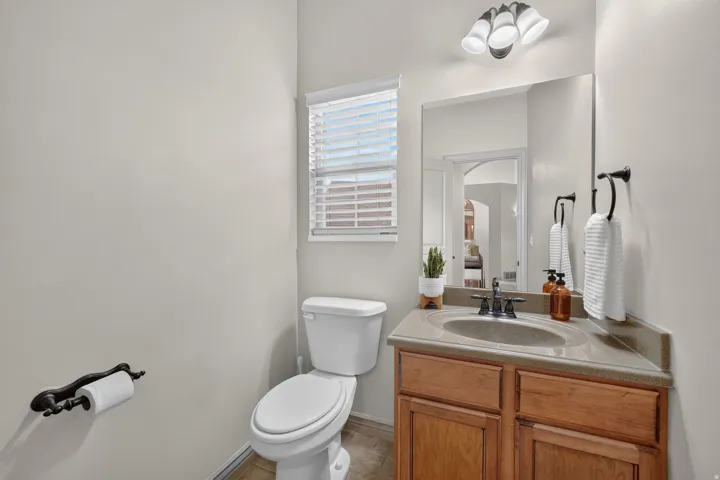 Corner vanity with a built-in sink, wood-finish cabinetry, and a vanity mirror