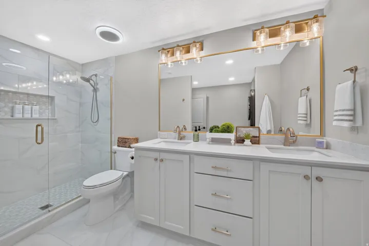 Dual vanity with white cabinetry, gold-finish hardware, and quartz countertops