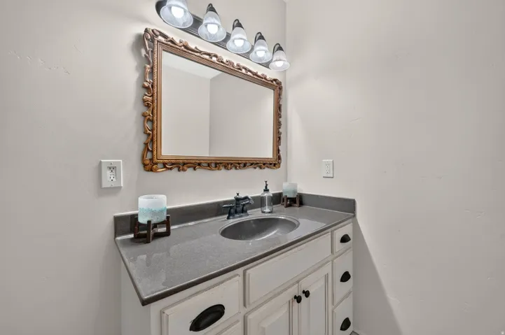 Vanity with stone countertop, integrated sink, and dark-finish faucet