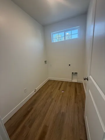Laundry room featuring wood-finish flooring, a transom window, and a paneled door with a round knob