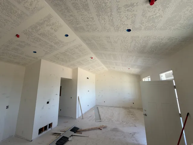 Vaulted ceiling, multiple recessed lighting placements, window openings, and a solid core door