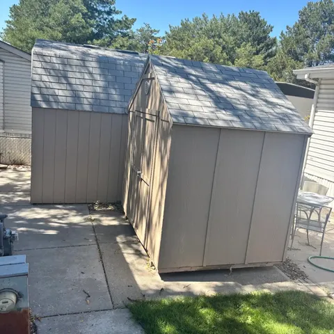 Two outdoor storage sheds featuring sloped roofs with shingle material and wood-style siding