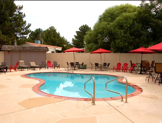 Freeform swimming pool with concrete decking, brick coping, and a privacy fence