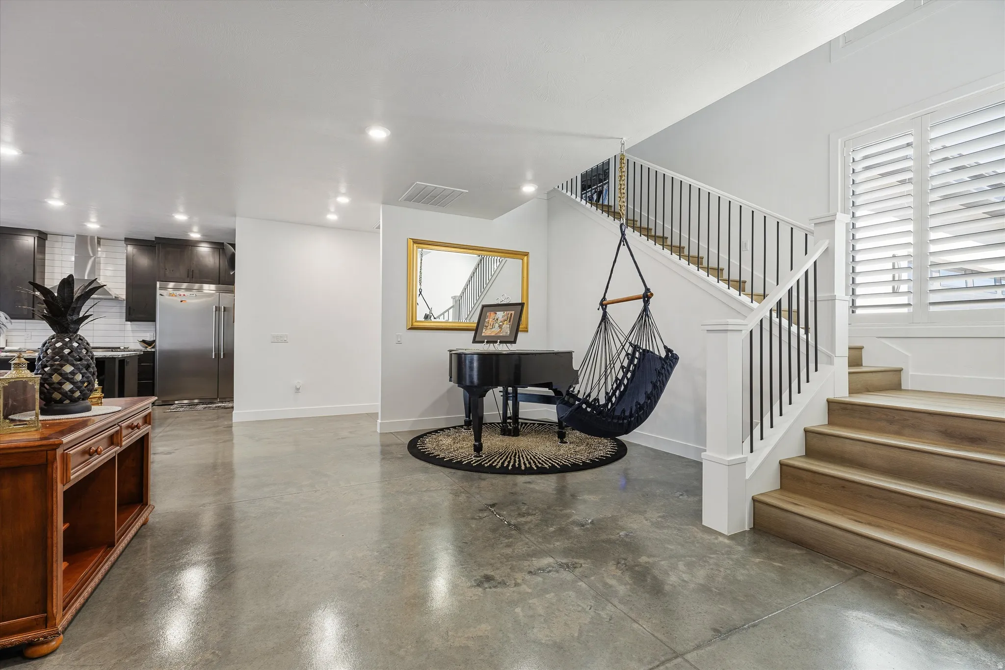 Polished concrete flooring, open staircase with wood-finish treads and metal balusters, and recessed ceiling lighting
