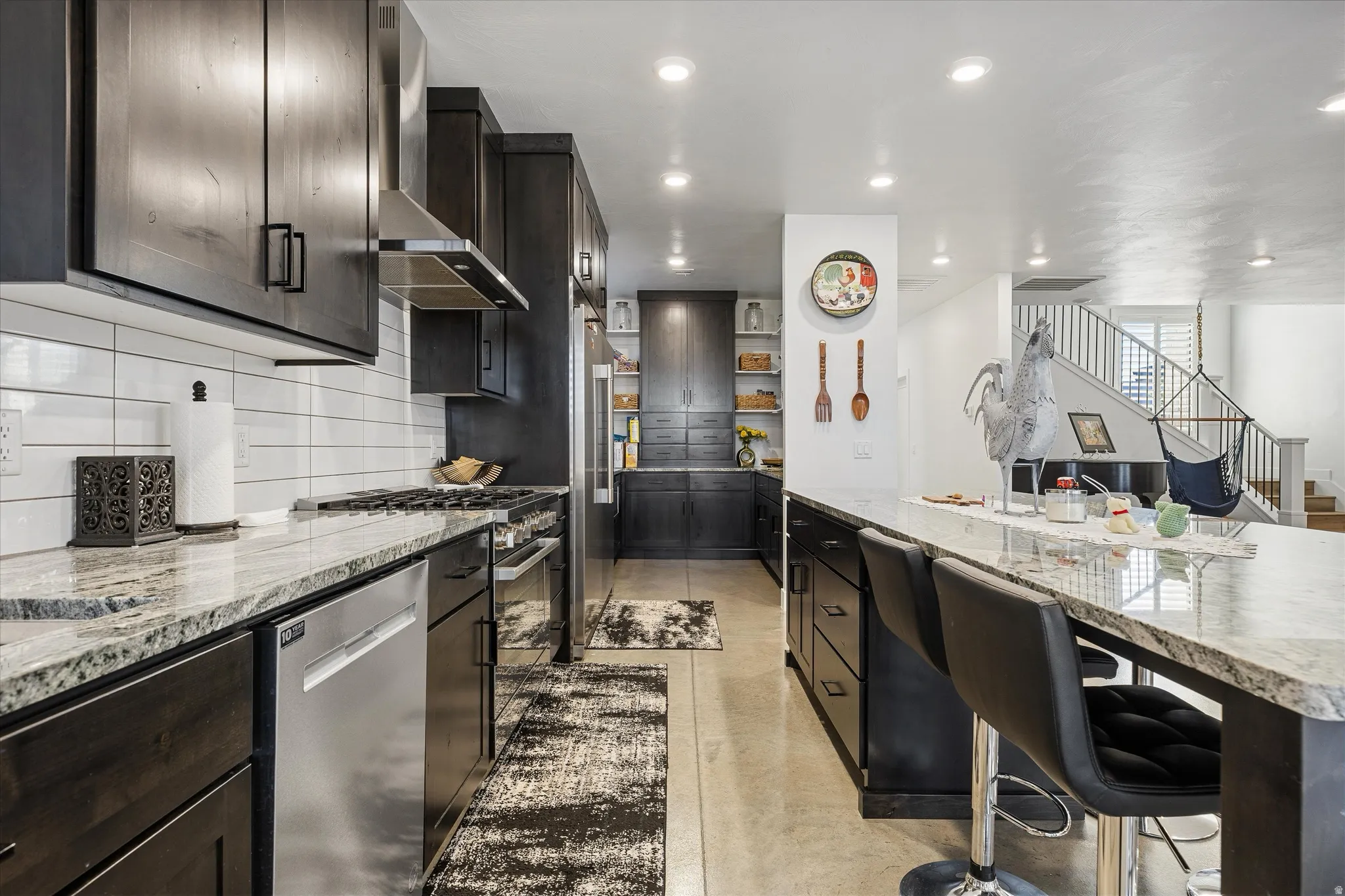 Kitchen featuring dark wood-finish cabinetry, stainless steel appliances, a tile backsplash, and light-toned countertops