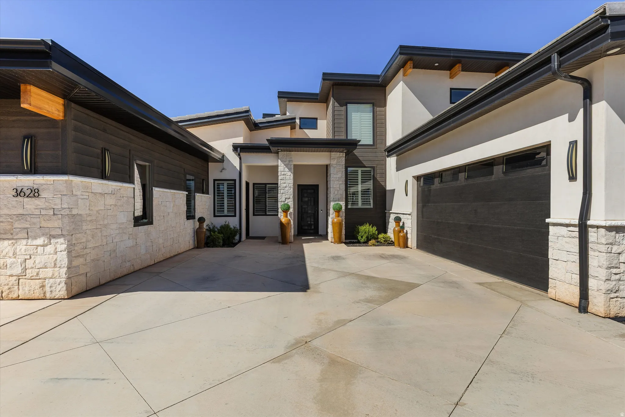 Contemporary exterior design featuring varied rooflines, stucco and stone-finish siding, and multiple garage doors