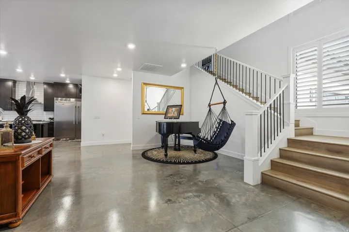 Polished concrete flooring, open staircase with wood-finish treads and metal balusters, and recessed ceiling lighting