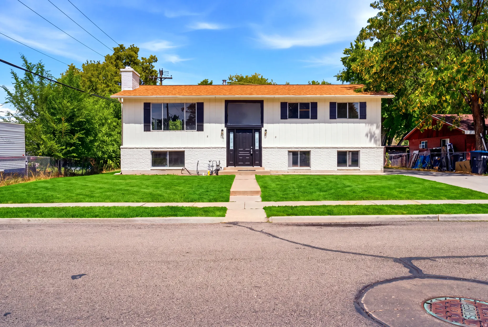 Two-story property with a bright orange roof and white siding, featuring a neatly maintained lawn