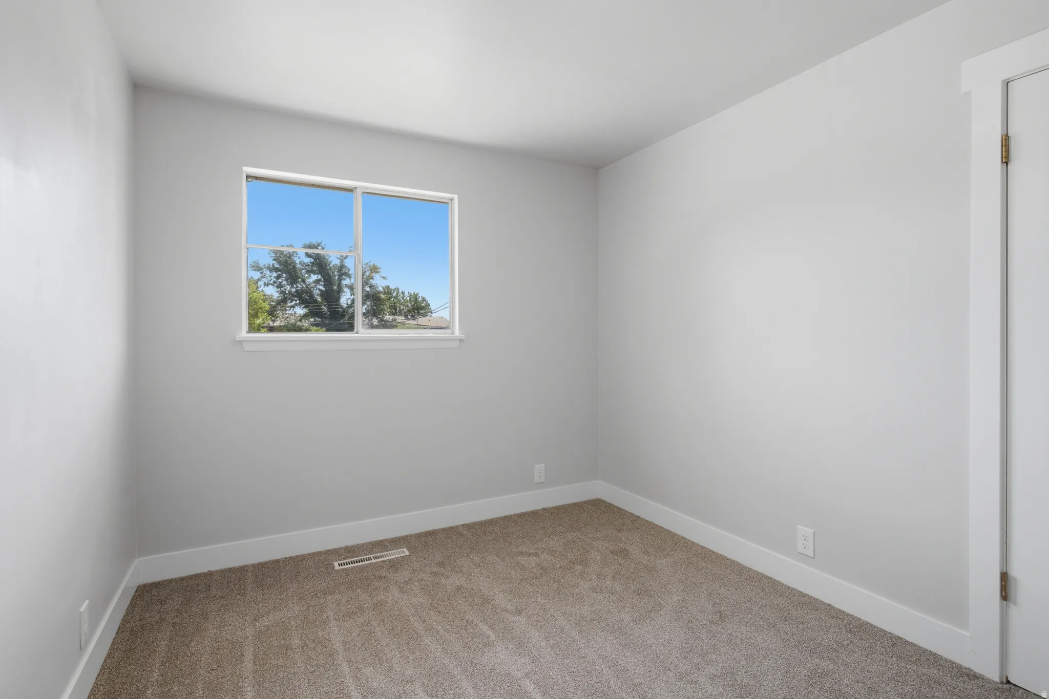 Carpeted flooring, white walls, and a window with white trim