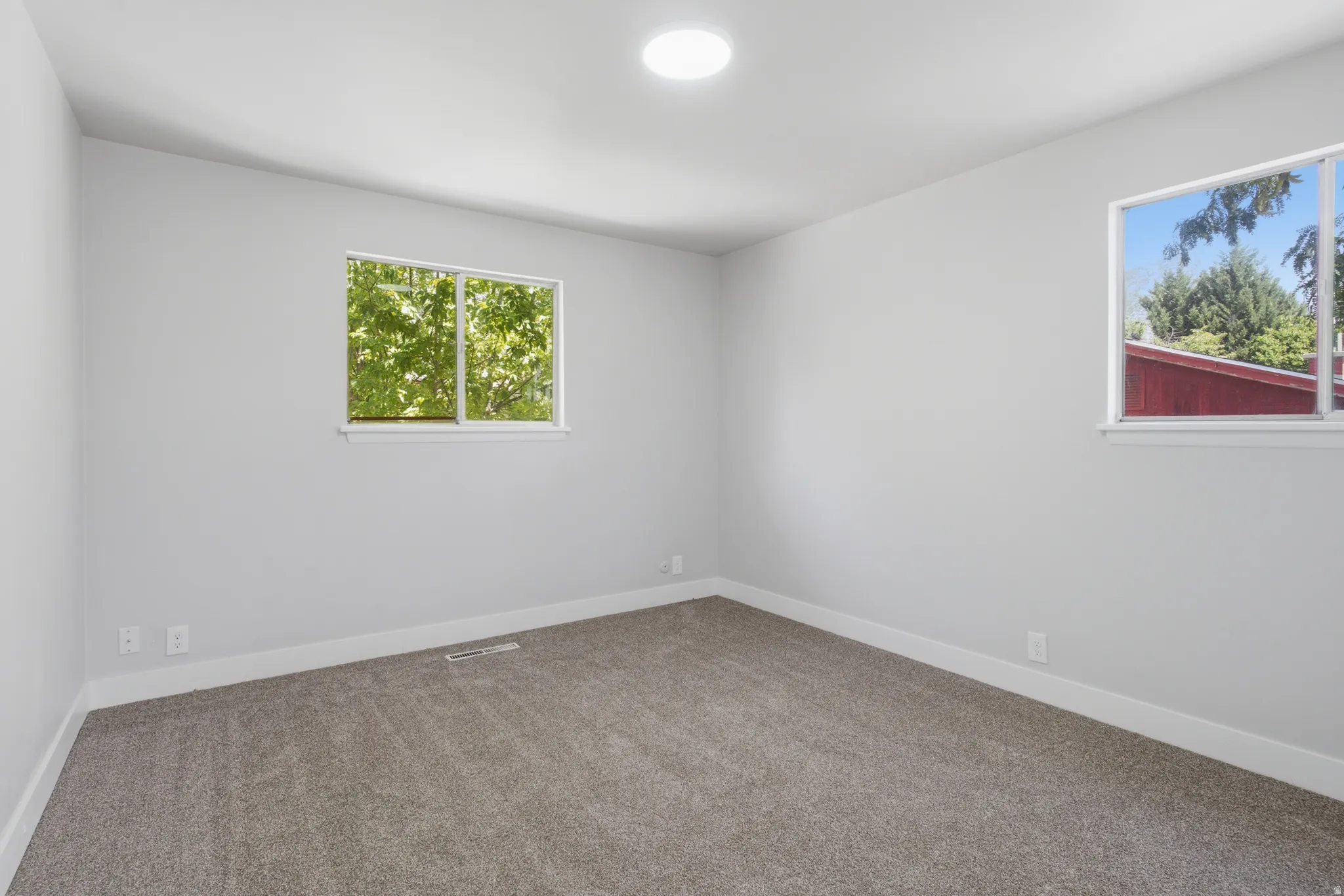 Neutral gray walls with white trim, two windows, and recessed ceiling lighting