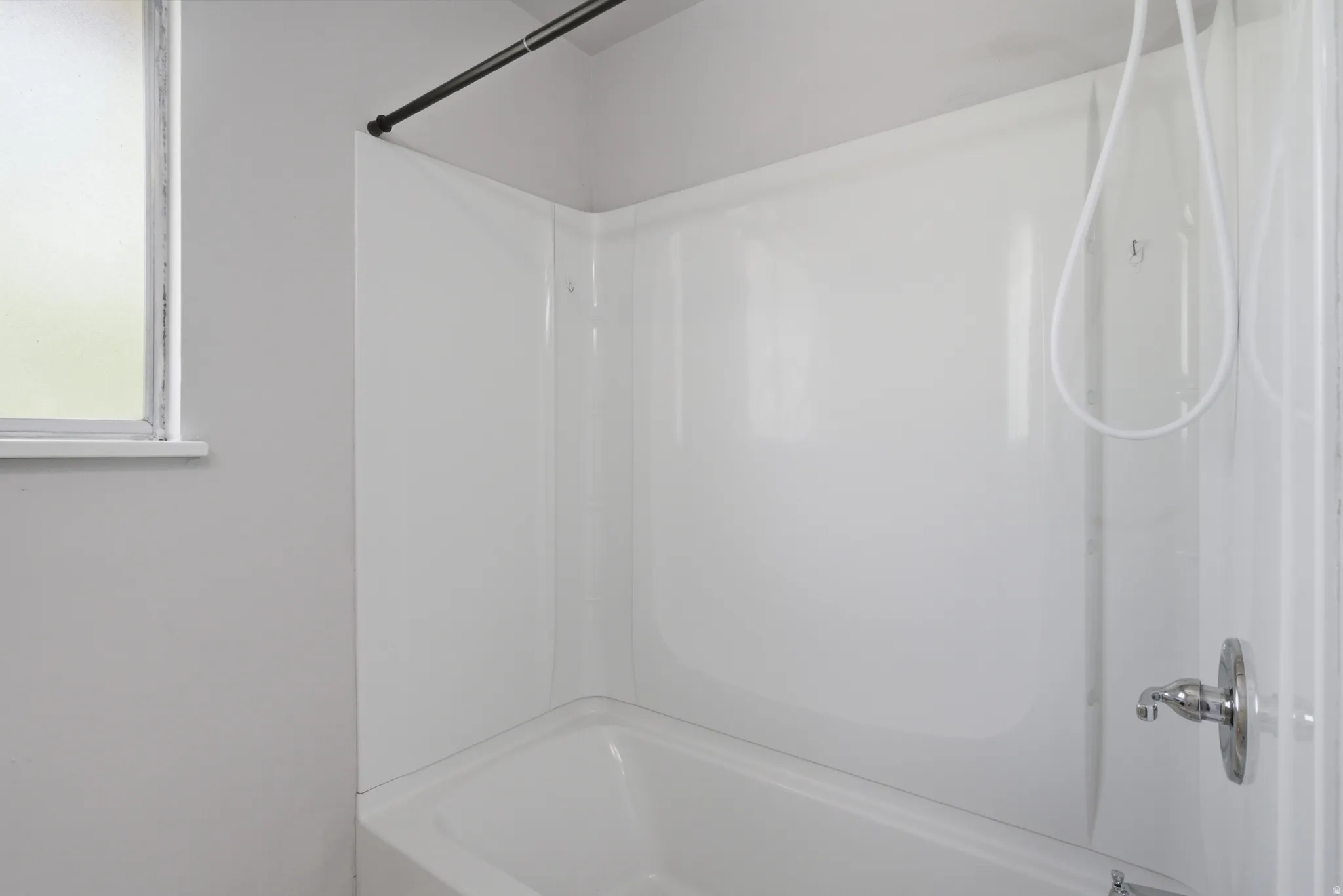 Bathtub shower combination with a white acrylic surround and a frosted window