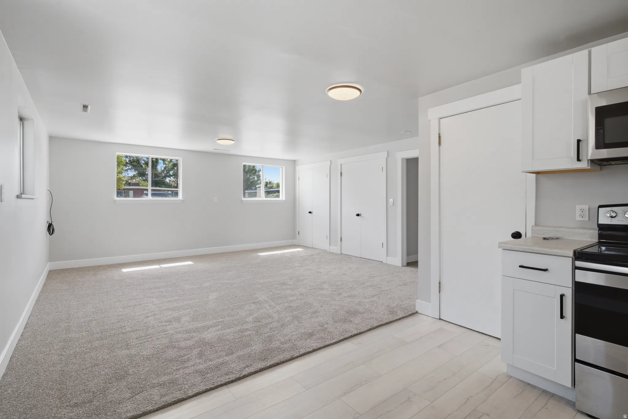 Recessed lighting, wood-finish flooring, white cabinetry, stainless steel appliances, and updated hardware