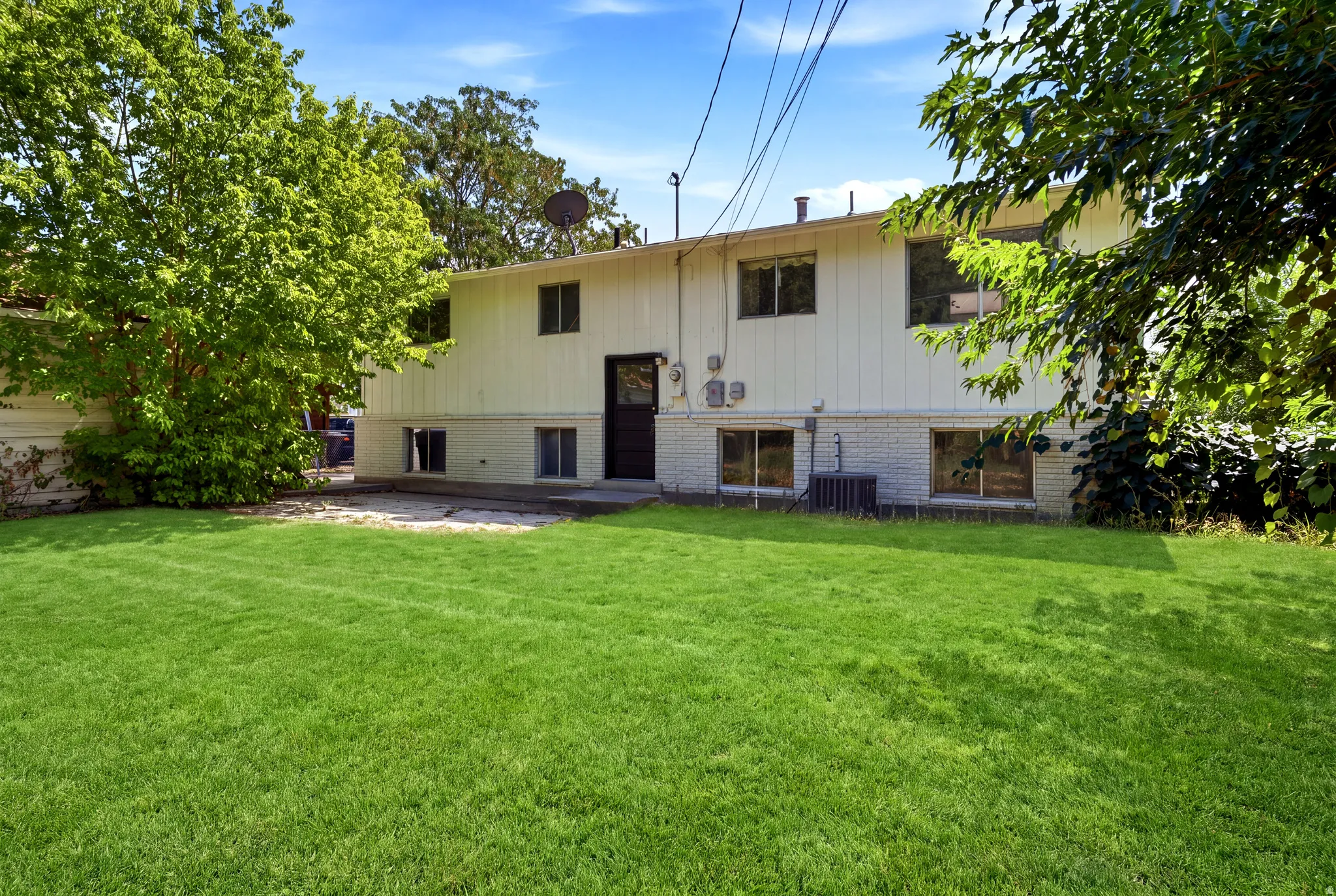 Expansive lawn area with mature trees and a concrete patio