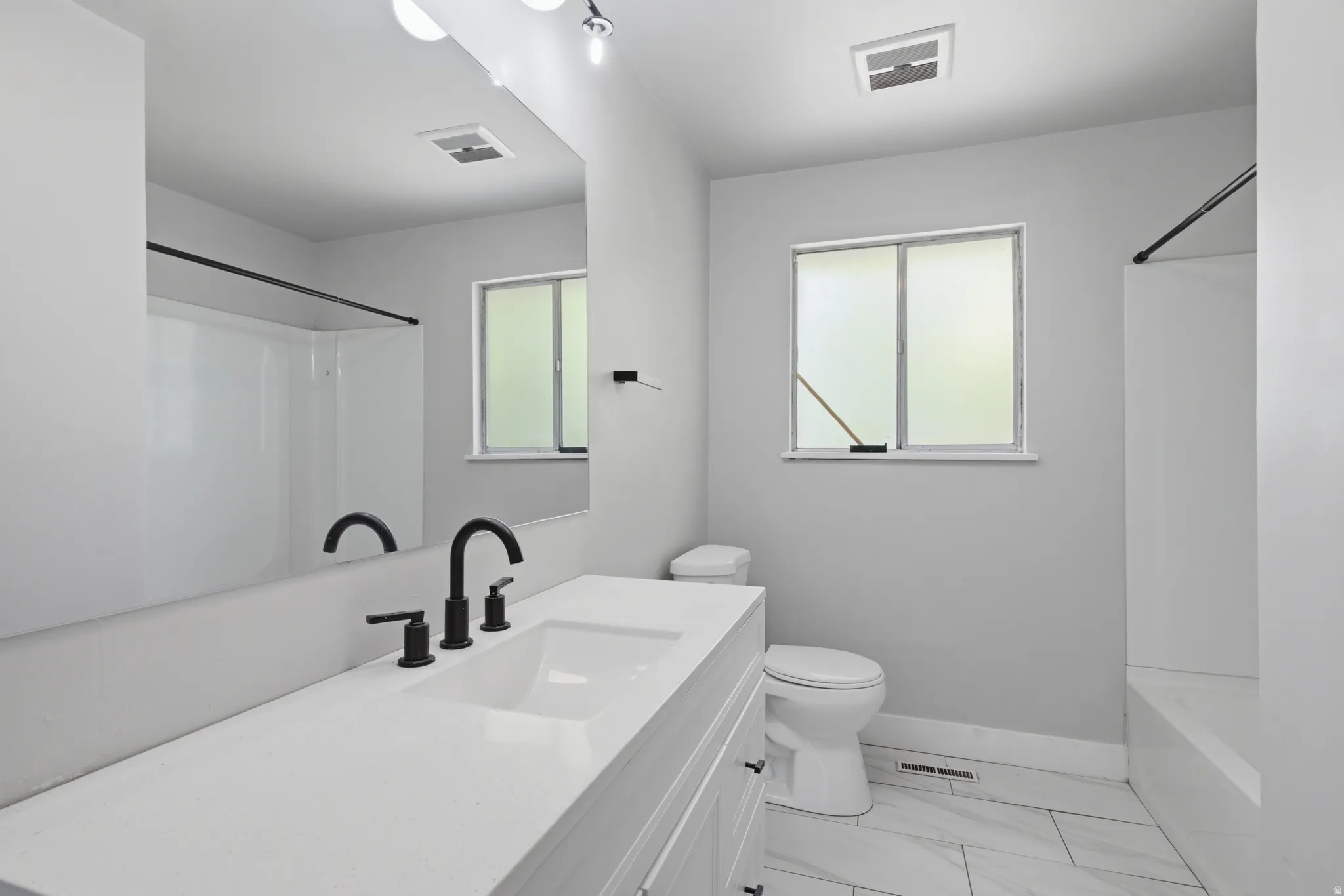 White vanity with an integrated rectangular sink, matte black faucet, and full-width mirror
