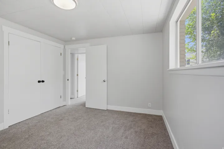 Neutral gray wall paint, light gray carpet, white trim, white doors, and a window