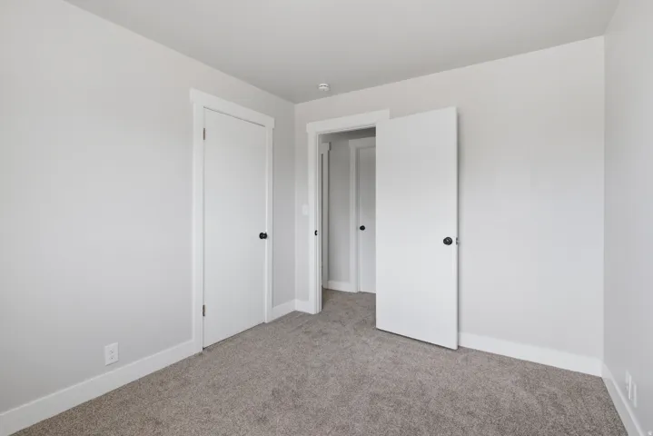 Light gray wall paint, gray carpet, white trim, white interior doors, and black door hardware