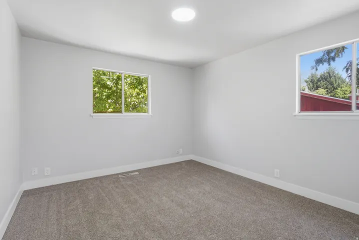 Neutral gray walls with white trim, two windows, and recessed ceiling lighting