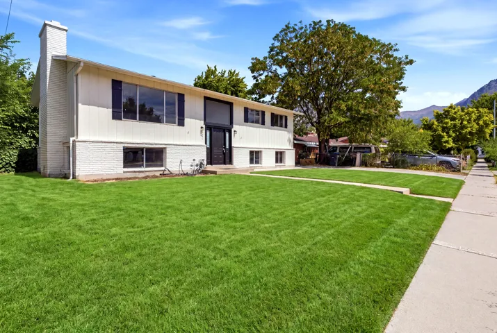 Split-level residence featuring a white painted brick exterior and dark framed windows