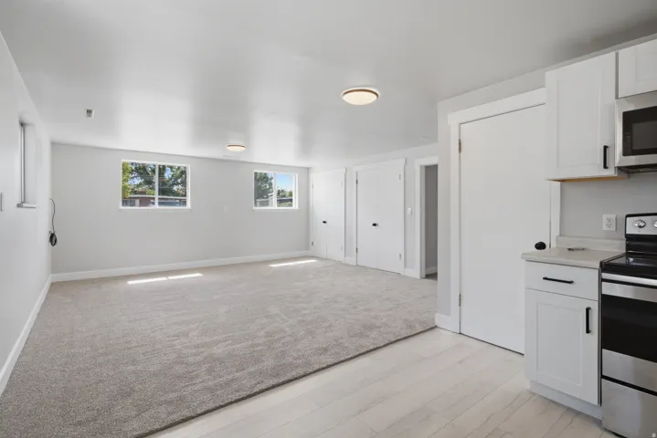 Recessed lighting, wood-finish flooring, white cabinetry, stainless steel appliances, and updated hardware