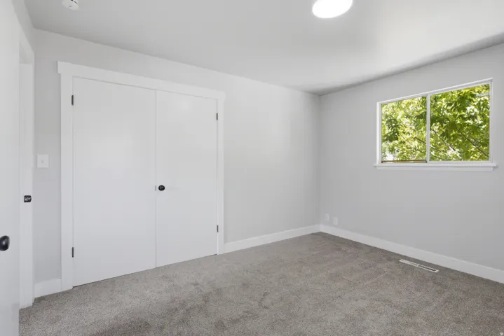 Gray-toned carpeting, white baseboards, and a double-door closet with dark hardware