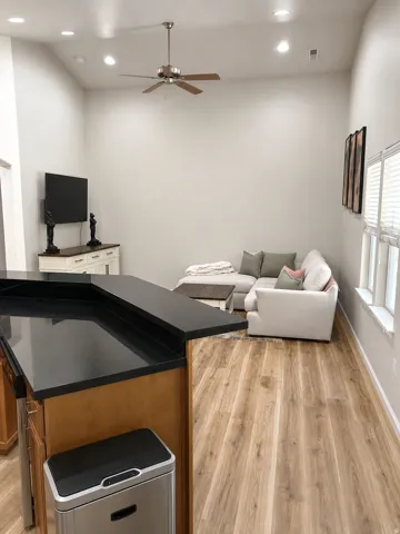 Vaulted ceilings with recessed lighting and a ceiling fan, wood-finish flooring, and black countertops