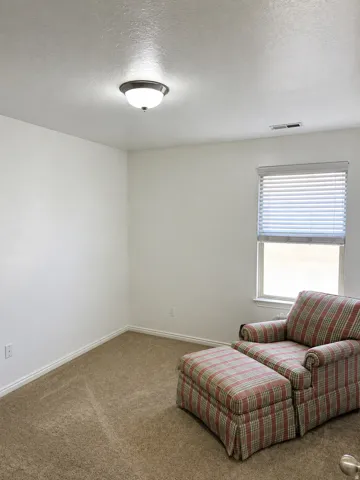 Recessed window with white blinds, neutral carpet flooring, and a flush-mount ceiling light fixture. Matching new laminate wood flooring available for install.