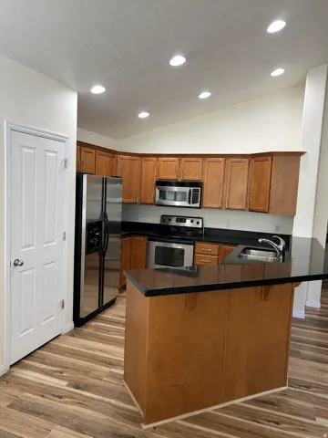 Kitchen featuring wood-finish flooring, recessed lighting, maple cabinetry, and stainless steel appliances