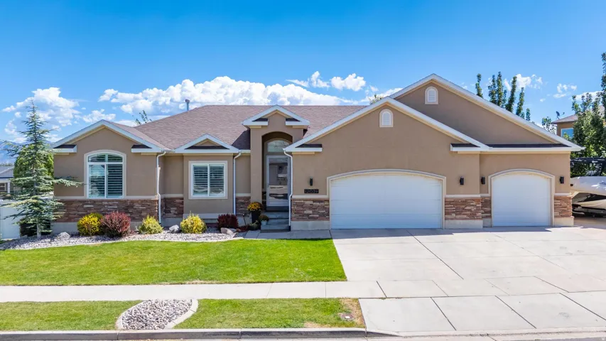 Stucco exterior with stone accent, arched entry, and a multi-car driveway