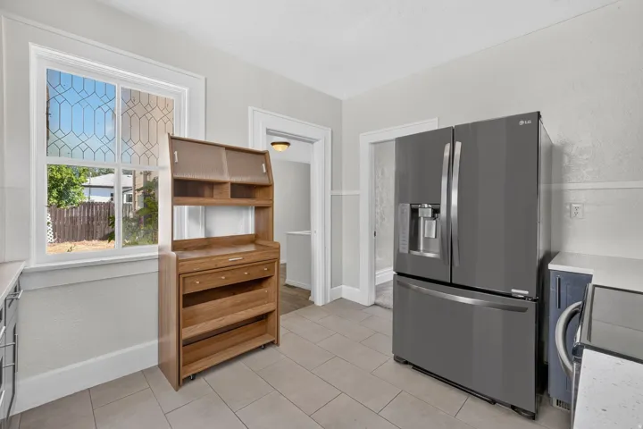 Tile flooring, modern refrigerator, white window trim, and baseboard trim