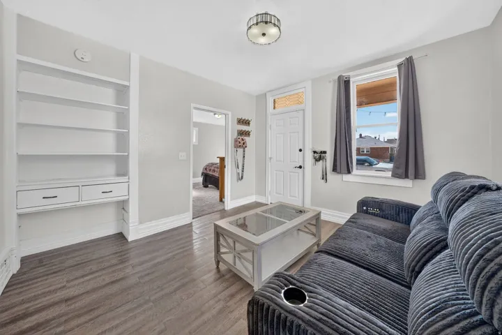 Built-in shelving with integrated drawers, wood-finish flooring, a transom window over the entry door, and a ceiling-mounted light fixture